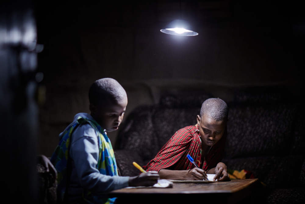 Two boys working under a lamp